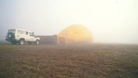 Lockdown shot of car and hot air balloon on the field Video stock 122451772