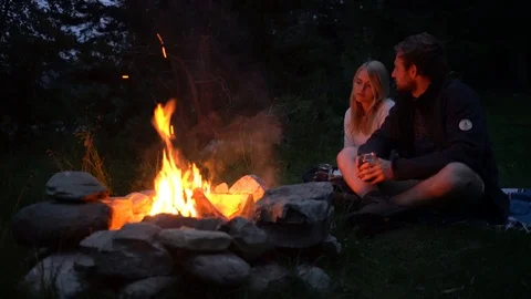 Lockdown shot of a couple sitting by the bonfire Stock Footage 114883094