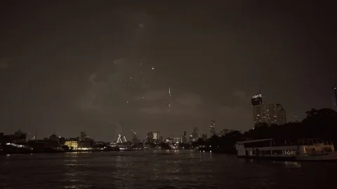 Lockdown shot of firework exploding over buildings in city by river against sky Stock Footage 129259931