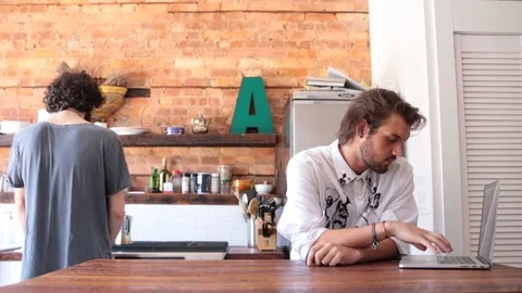 Lockdown shot of gay man preparing coffee for boyfriend working on laptop Video stock 114859817