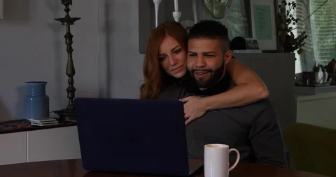 Lockdown shot of girlfriend embracing boyfriend while working on laptop at home Stock Footage 119972774
