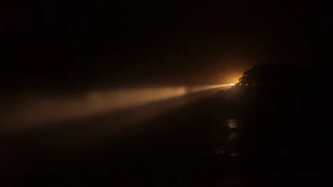 Lockdown shot of illuminated lighthouse by sea against sky at night Stock Footage 96225178