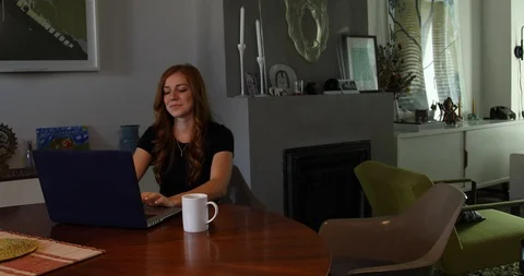 Lockdown shot of man greeting girlfriend working on laptop at home Stock Footage 119975422