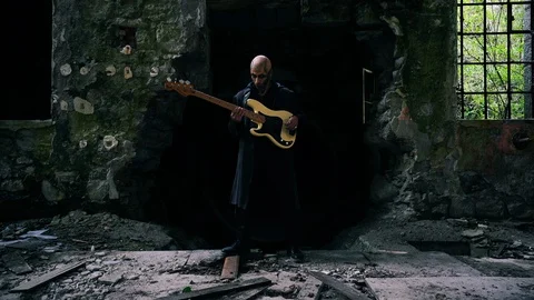 Lockdown shot of a man playing guitar in ruins of building Video stock 114885255