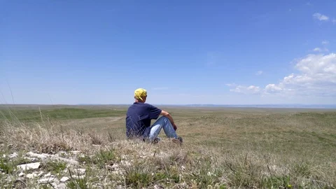 Lockdown shot of a man sitting in the desert Vídeo Stock 114884911