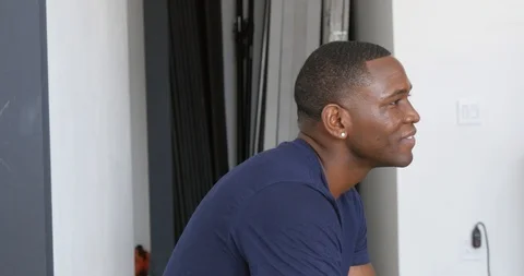 Lockdown shot of smiling man with arms crossed sitting at home Stock Footage 114862816