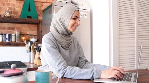 Lockdown shot of smiling young freelancer in hijab working on laptop Stock Footage 114860069