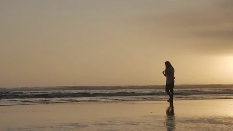 Lockdown shot of woman throwing something to sea Stock Footage 120081322