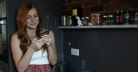 Lockdown shot of woman using smartphone while standing in kitchen Stock Footage 119770768