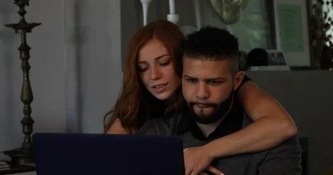 Lockdown shot of young couple embracing and talking while working on laptop Stock Footage 119973495