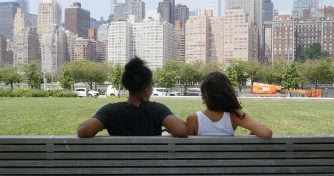 Lockdown shot of young couple sitting on park bench in city Stock Footage 120062922