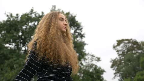 Lockdown shot of young curly haired woman stretching in park in slow motion Video stock 114873842