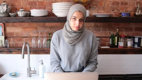 Lockdown shot of young freelancer wearing hijab using laptop in kitchen Video stock 114860133