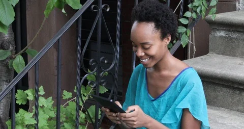 Lockdown shot of young woman using digital tablet while sitting on steps Stock Footage 120044266