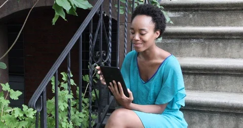 Lockdown shot of young woman using digital tablet while sitting on steps Stock Footage 120096370