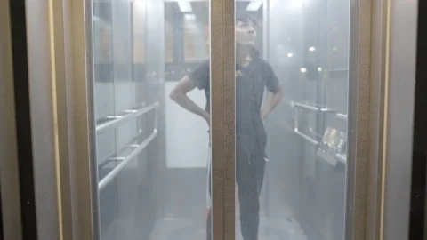 Lockdown Of A Young Man Standing Inside A Glass Elevator As It Starts To Ascend, Stockbeeldmateriaal 154594048