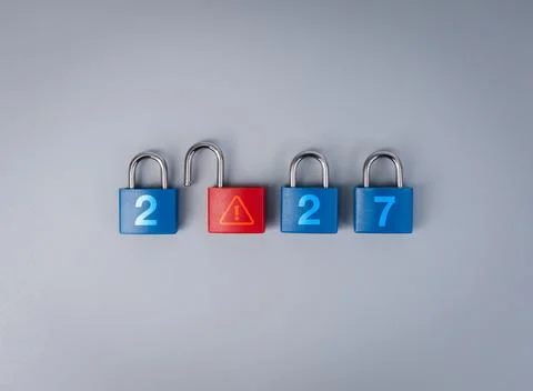 Locked blue padlocks surround open red warning lock with 2027 new year conc.. Stock Photos