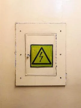 Locked electrical panel on the wall painted with yellow oil paint. There is a Stock Photos