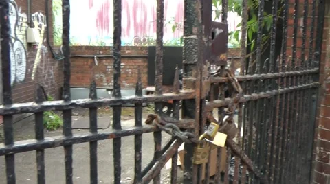 Locked Gate to Scruffy Yard with brick walls and graffiti tags Stock Footage 41423485