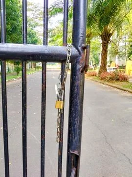 Locked Iron Gate with Chain and Brass Padlock Restricting Access to Road Stock Photos