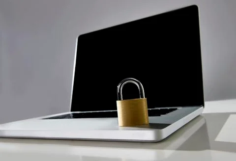 Locked lock on keyboard computer laptop with blank black screen  copy space Stock Photos