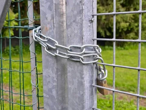 A locked metal gate, secured with a silver chain and padlock, for protection. Stock Photos