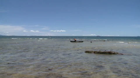 Locked off mid shot of a man pulling a boat along in water Stock Footage 310541054