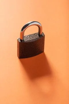 Locked padlock diagonal view on orange backgound, copyspace. Stock Photos