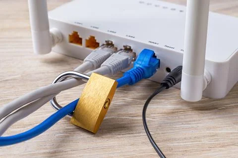 Locked padlock on network cables connected to white Wi-Fi wireless router. Stock Photos