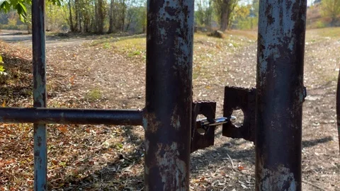 Locked padlock on rusty metal gate on a sunny autumn day. Stock Footage 124257223