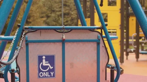 Locked swing for wheelchair users on an empty playground Stock Footage 141523229