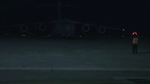 Lockheed C-130 directed by airman on runway at night Stock Footage 111848936