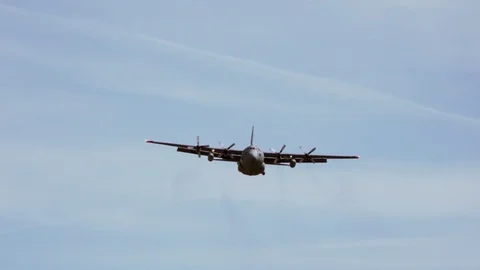 Lockheed C-130 flies above a large field 1 Stock Footage 111849122