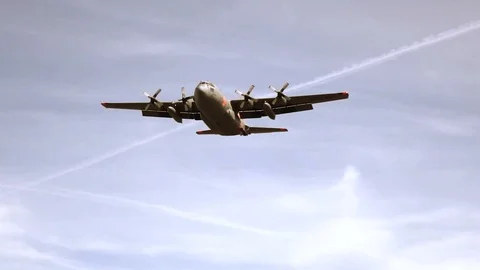 Lockheed C-130 flies above a large field 3 Stock Footage 111849128