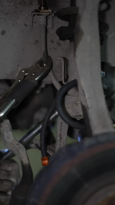 Locking pliers clamp an old brake hose inside wheel well. Stock Footage 345708409