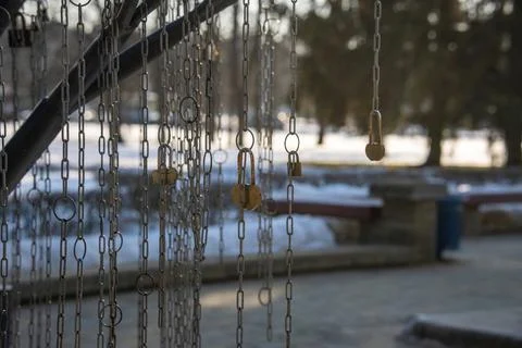 Locks threaded through chain links hanging in a city park. Loving couples han Stock Photos