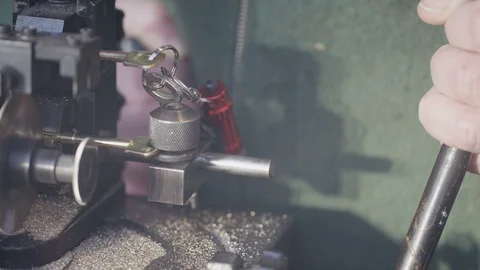 Locksmith cutting a duplicate key with machinery in the workshop Видео 102277286