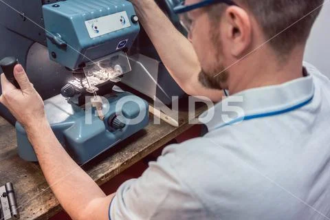 Locksmith cutting key with his machine ~ Hi Res #120736003