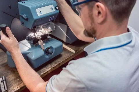 Locksmith cutting key with his machine Stock Photos