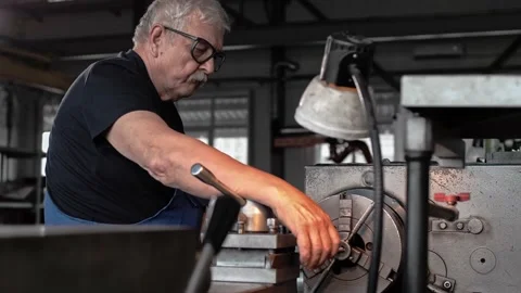 Locksmith with extensive experience is working at a lathe at a mature age Stock Footage 212384871