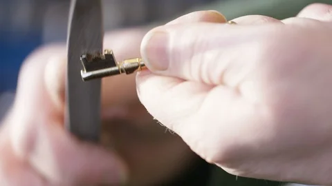 Locksmith filing the edges of a new duplicate key after cutting it Stock Footage 102288526