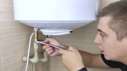 A locksmith fixes a boiler that is not working. The worker will check the electr Stock Footage 138930495
