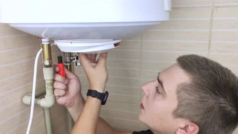 A locksmith fixes a boiler that is not working. The worker will check the electr Stock Footage 138930579