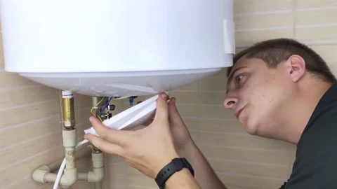 A locksmith fixes a boiler that is not working. The worker will check the electr Video stock 138930613