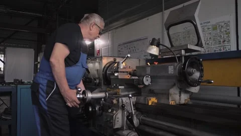 Locksmith of pre-retirement age works on a lathe in a shop on the factory floor Stock Footage 212384868