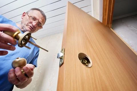 Locksmith preparing to insert door knob assembly into predrilled hole in wo.. Stock Photos
