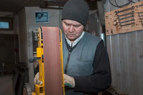 Locksmith processes a part on an emery machine 스톡 사진