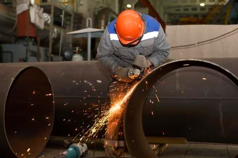 Locksmith processes pipe edge with electric hand grinder Stock Photos