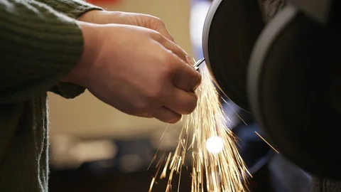 Locksmith smoothing the edges of a freshly cut key on a sanding belt Stock Footage 102259111