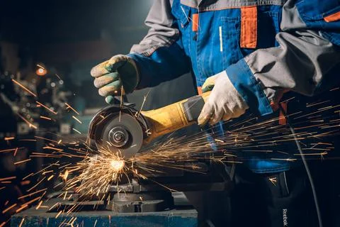 Locksmith in special clothes and goggles works in production. Metal processing Stock Photos
